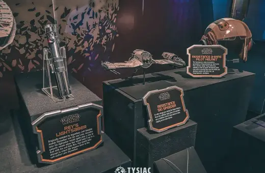 Miecz świetlny Rey, hełm pilota A-winga i pojazd Resistance Ski Speeder z wystawy Star Wars Galaxy's Edge.