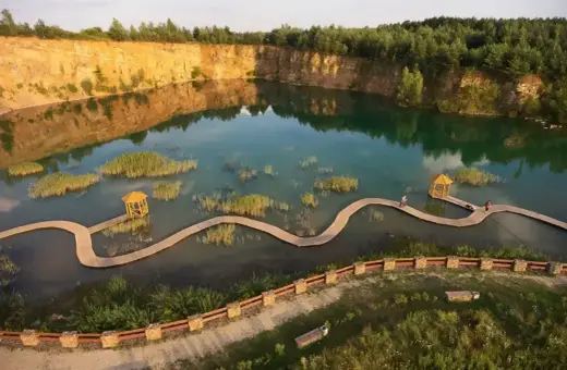 Malowniczy park Gródek z drewnianymi kładkami wijącymi się pośród turkusowej wody i wysepek z trzcinami.