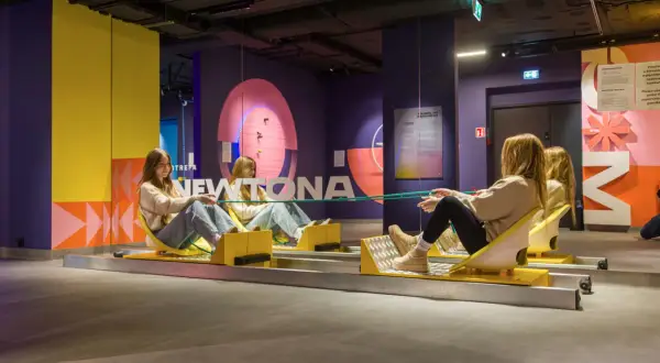 Dwie dziewczyny na wózkach w muzeum grawitacji, eksperymentują z liną.