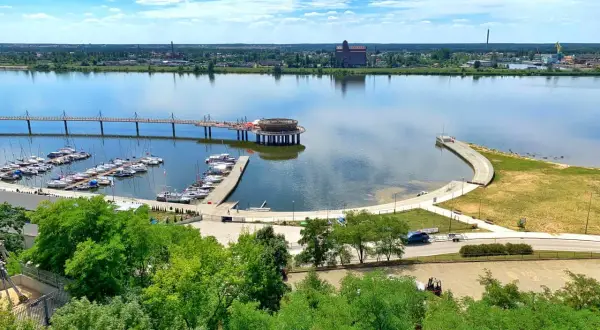 Płock co zobaczyć: malownicza marina z żaglówkami, nowoczesny deptak nad Wisłą i industrialne krajobrazy w tle.