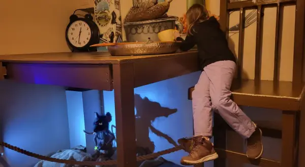 Dziewczynka na gigantycznym krześle odkrywa ukrytą krainę w Kołobrzegu. Pod stołem czeka na nią myszka.