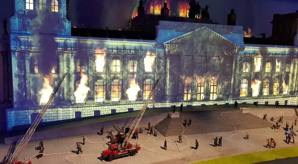 Miniaturowy pożar Reichstagu w **little big city Berlin**. Strażacy walczą z płomieniami, a dym unosi się w mroku.