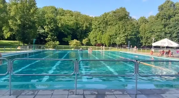 Słoneczny dzień nad basenem w Bytomiu. Woda kusi chłodem, a wokół zielone drzewa.