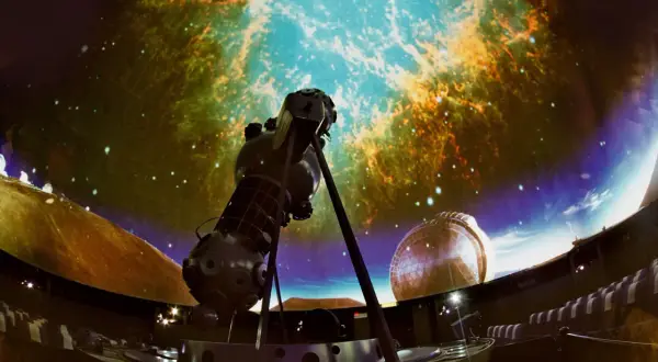Wielki projektor gwiazd w centrum, otoczony siedzeniami, tworzy magiczne planetarium dla dzieci.