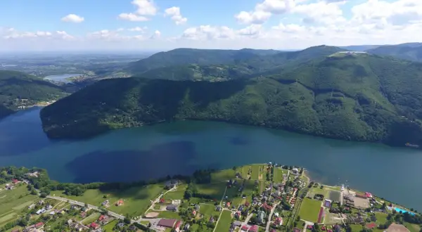Widok z lotu ptaka na Jezioro Międzybrodzkie z malowniczą plażą i otaczającymi je zielonymi wzgórzami.