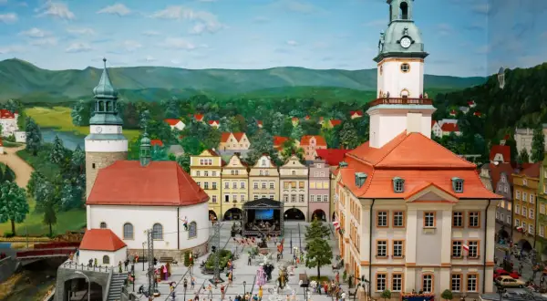Miniaturowa kolejkowo scena z Jeleniej Góry, z ratuszem, kościołem i tłumem ludzi na rynku.