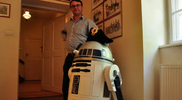 W muzeum Star Wars R2-D2 w wojskowym kapeluszu pozuje z mężczyzną.
