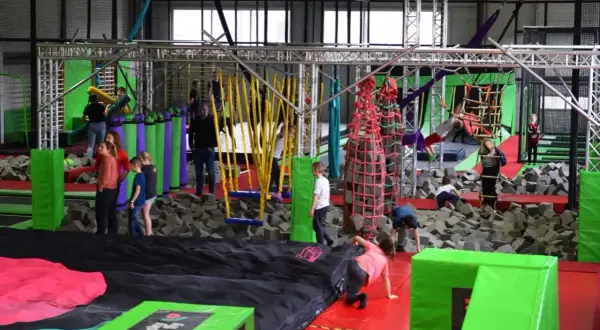 Wesoła zabawa w parku rozrywki Flysky! Dzieci skaczą, wspinają się i pokonują przeszkody na trampolinach i w basenie z gąbkami.