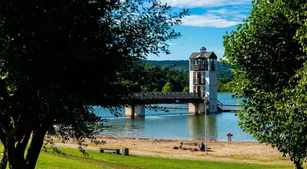 Stara Morawa zalew z wieżą widokową i mostem. Na piaszczystej plaży odpoczywają ludzie.