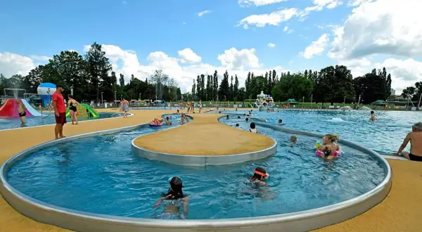Rodzinna zabawa w moczydło park wodny. Dzieci pluskają się w wodzie, ślizgają na zjeżdżalniach, a dorośli odpoczywają na brzegu.