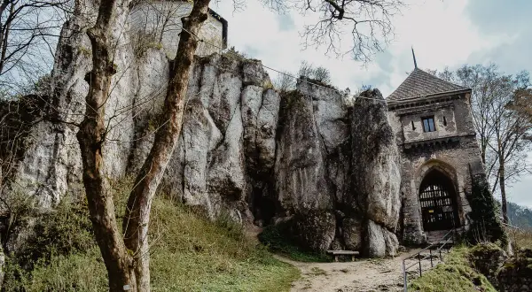 Ojcowski Park Narodowy atrakcje: ruiny zamku na skale, kamienna wieża bramna i ścieżka wśród zieleni.