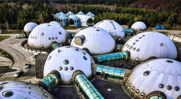 Alvernia Planet zwiedzanie: futurystyczne kopuły i szklane tunele w otoczeniu lasu.