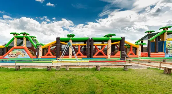 Kolorowy park rozrywki zachodniopomorskie z dmuchanymi zjeżdżalniami i przeszkodami w kształcie dżungli.