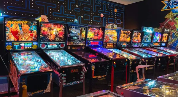 Rząd automatów do gry w stylu retro, w tym maszyny Baywatch i Terminator, tworzy klimat prawdziwego **arcade museum**.