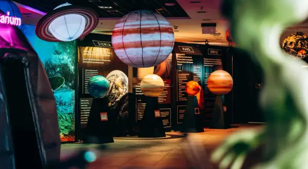 Modele planet i pierścieni Saturna w kosmo parku. W tle tablice informacyjne o Ziemi, Marsie i Jowiszu.