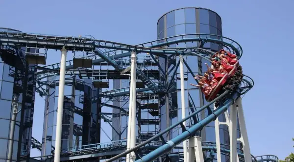 Wesoła kolejka górska z pasażerami wjeżdża na szczyt przy nowoczesnych budynkach w Europa Park Niemcy.