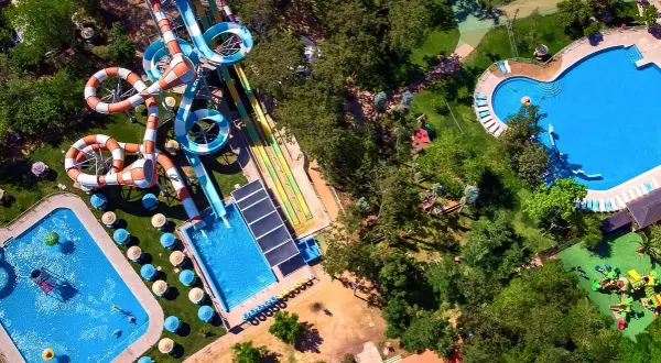 Widok z lotu ptaka na Santiago Aquapark: kolorowe zjeżdżalnie, baseny i zielone tereny rekreacyjne.