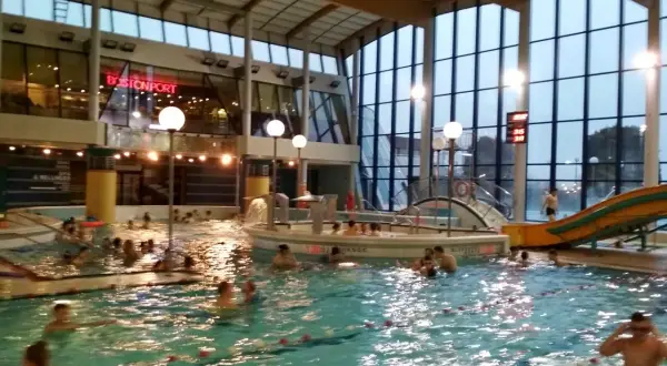 Ludzie pluskają się w basenie Warszawianka. W tle widać zjeżdżalnię i restaurację Bostonport.