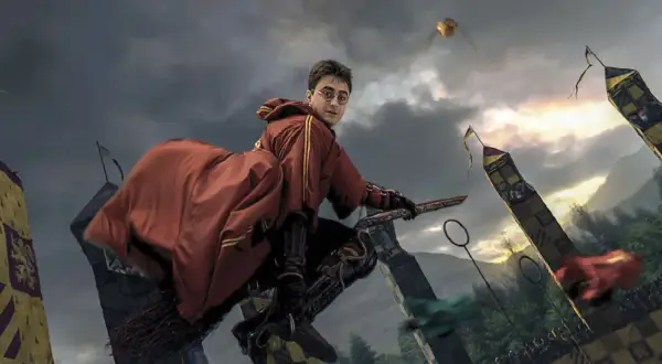 Harry Potter na miotle, w czerwonym szacie, ściga Złoty Znicz podczas meczu quidditcha. To scena z filmu "Harry Potter i Zakazana Podróż".