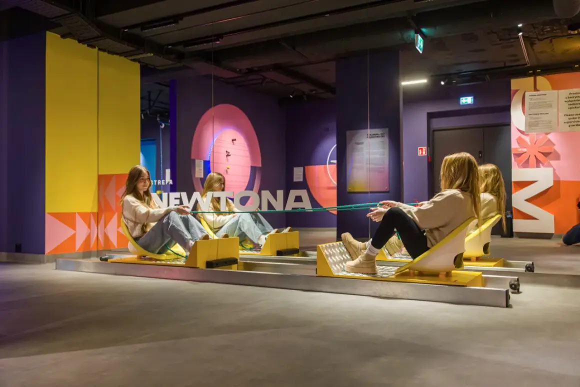 Dwie dziewczyny na wózkach w muzeum grawitacji, eksperymentują z liną.