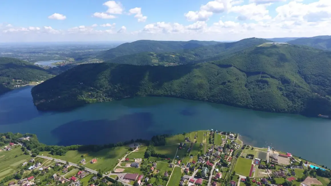 Widok z lotu ptaka na Jezioro Międzybrodzkie z malowniczą plażą i otaczającymi je zielonymi wzgórzami.