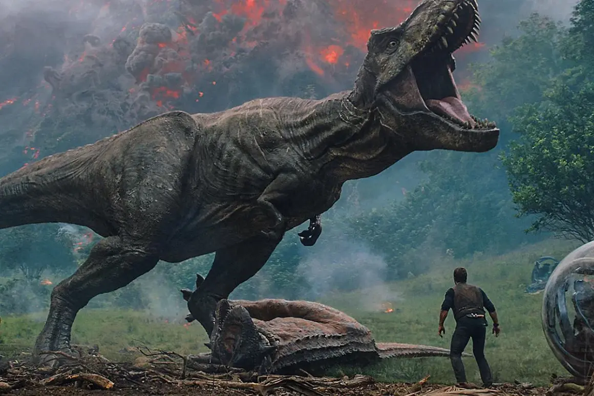Tyranozaur atakuje w parku rozrywki Jurassic World, człowiek stoi w obliczu chaosu, w tle wulkaniczna erupcja.