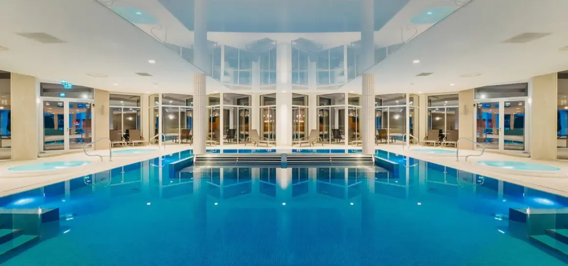 Wnętrze aquaparku Crystal Mountain z basenem, jacuzzi i leżakami.
