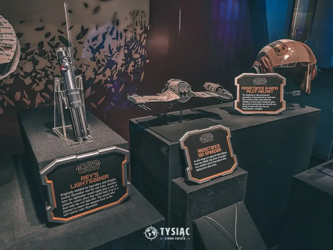 Miecz świetlny Rey, hełm pilota A-winga i pojazd Resistance Ski Speeder z wystawy Star Wars Galaxy's Edge.