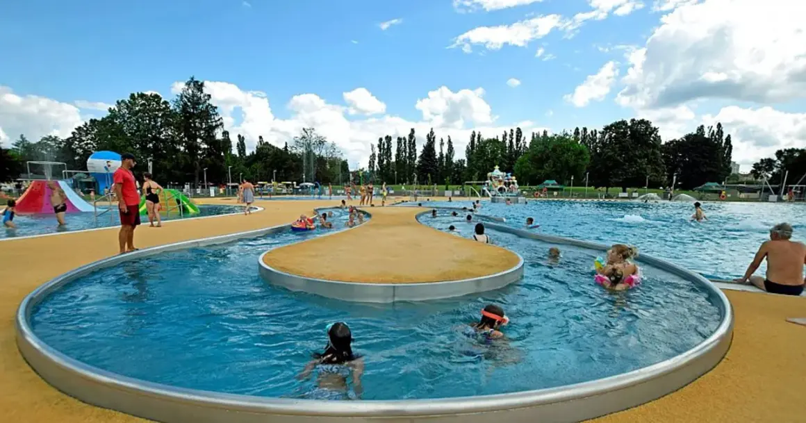 Rodzinna zabawa w moczydło park wodny. Dzieci pluskają się w wodzie, ślizgają na zjeżdżalniach, a dorośli odpoczywają na brzegu.