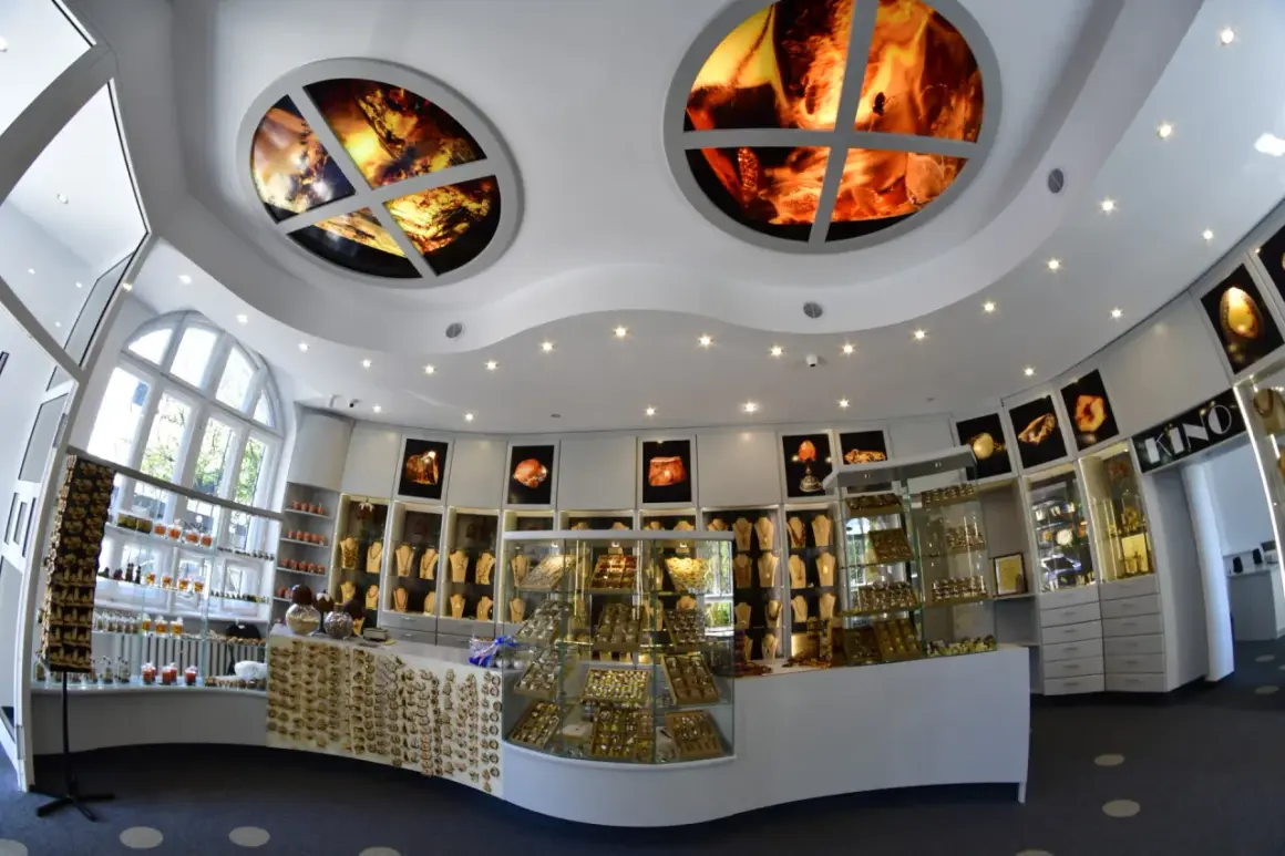 Wnętrze muzeum bursztynu Kołobrzeg. W gablotach błyszczą złote ozdoby, a na suficie widnieją okrągłe iluminacje z bursztynem.