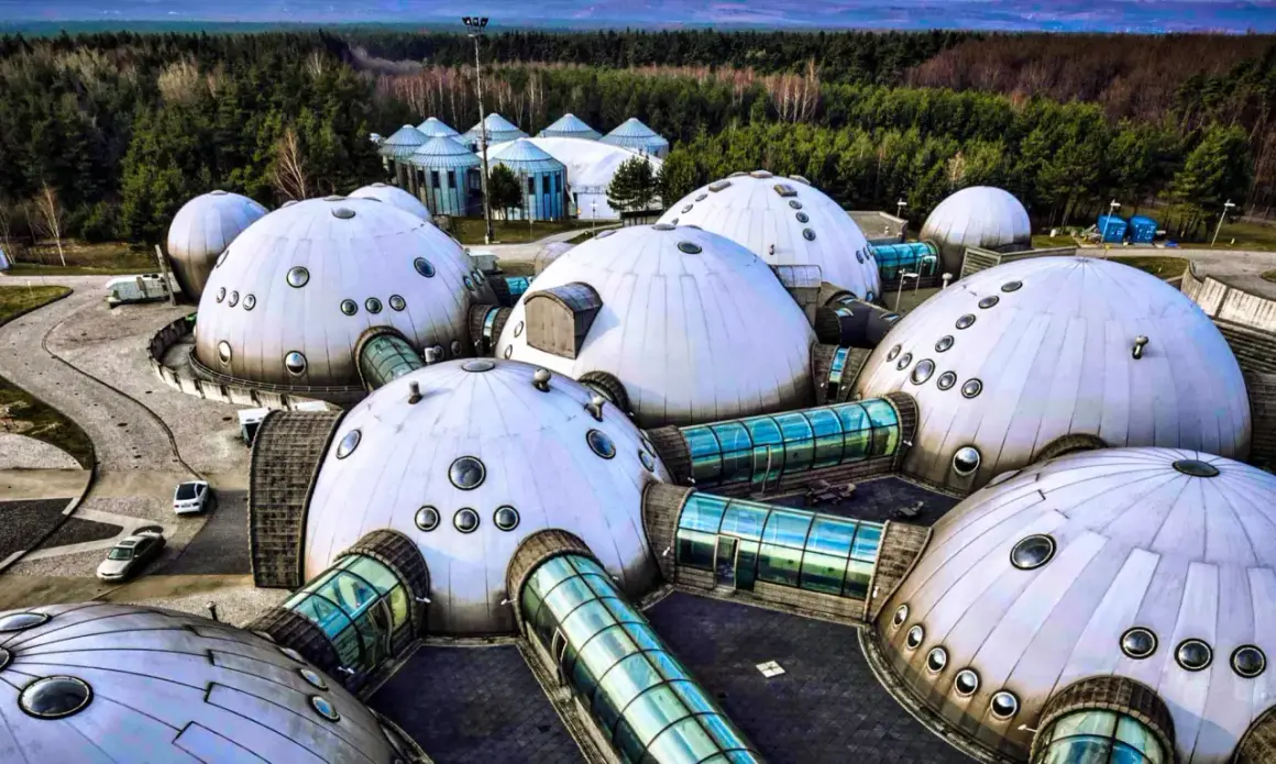 Alvernia Planet zwiedzanie: futurystyczne kopuły i szklane tunele w otoczeniu lasu.