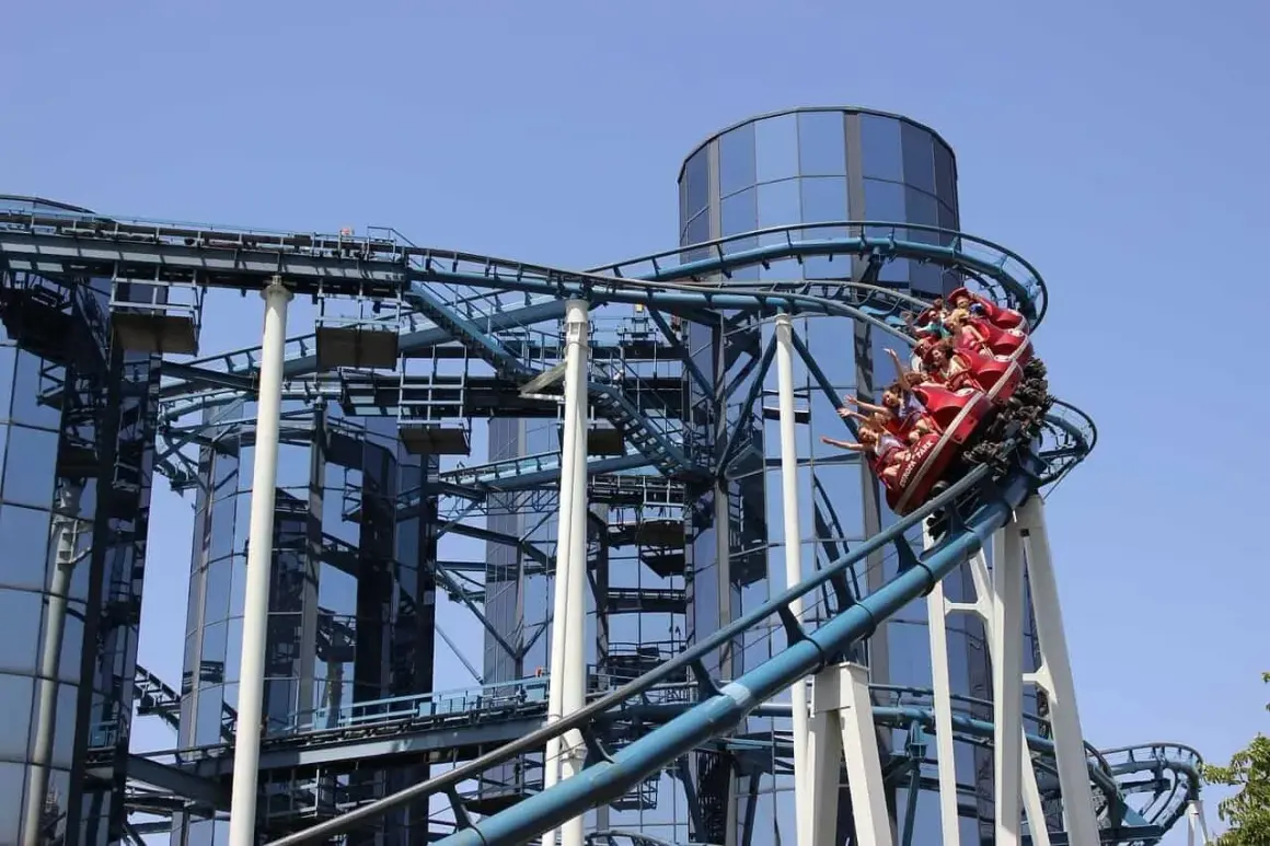 Wesoła kolejka górska z pasażerami wjeżdża na szczyt przy nowoczesnych budynkach w Europa Park Niemcy.