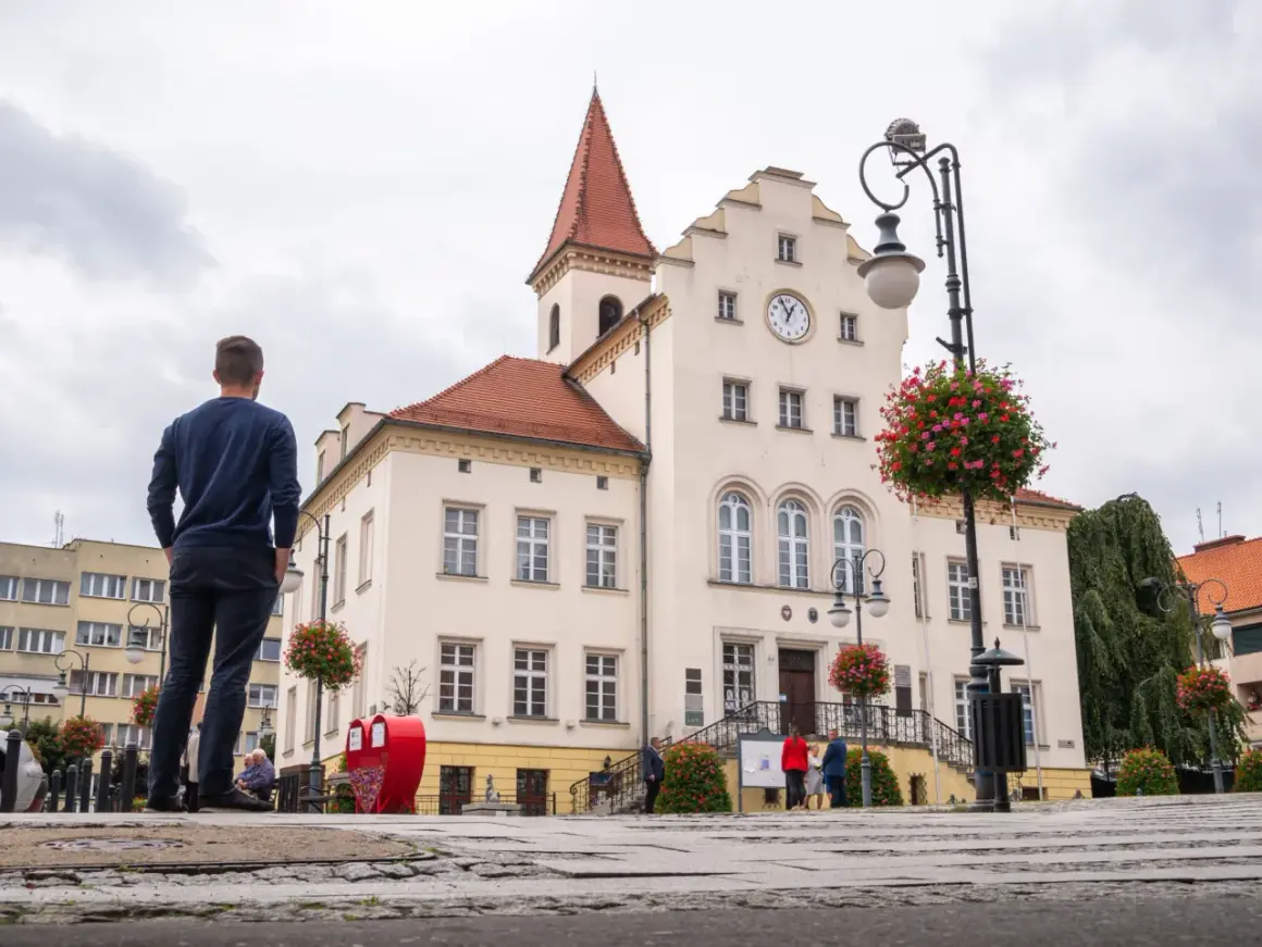 Mężczyzna patrzy na ratusz w Trzebnicy, jedno z głównych atrakcji miasta. W tle widać zegar i czerwone serca.