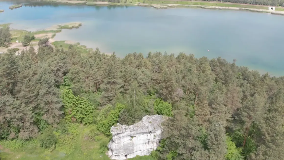 Malowniczy krajobraz z lasem sosnowym i skalną formacją, nad turkusowym zalewem Dźibice.
