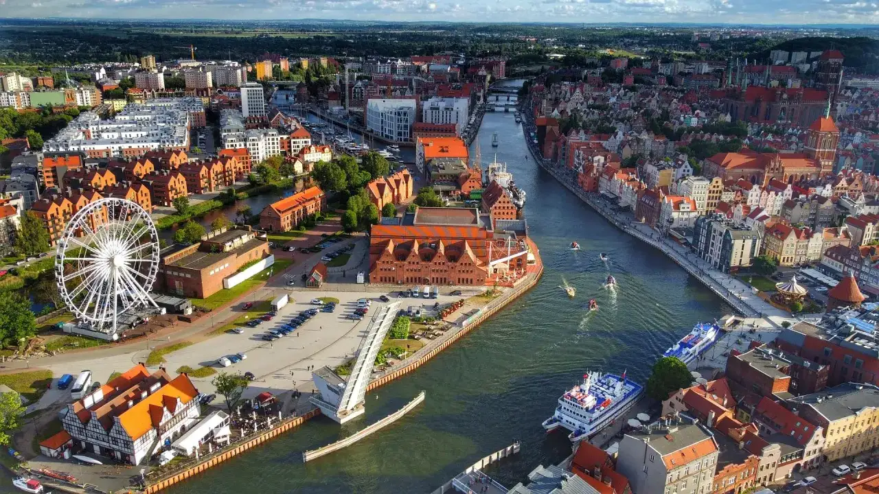 Widok na Gdańsk z kołem widokowym i rzeką Motławą pod bursztynowym niebem.