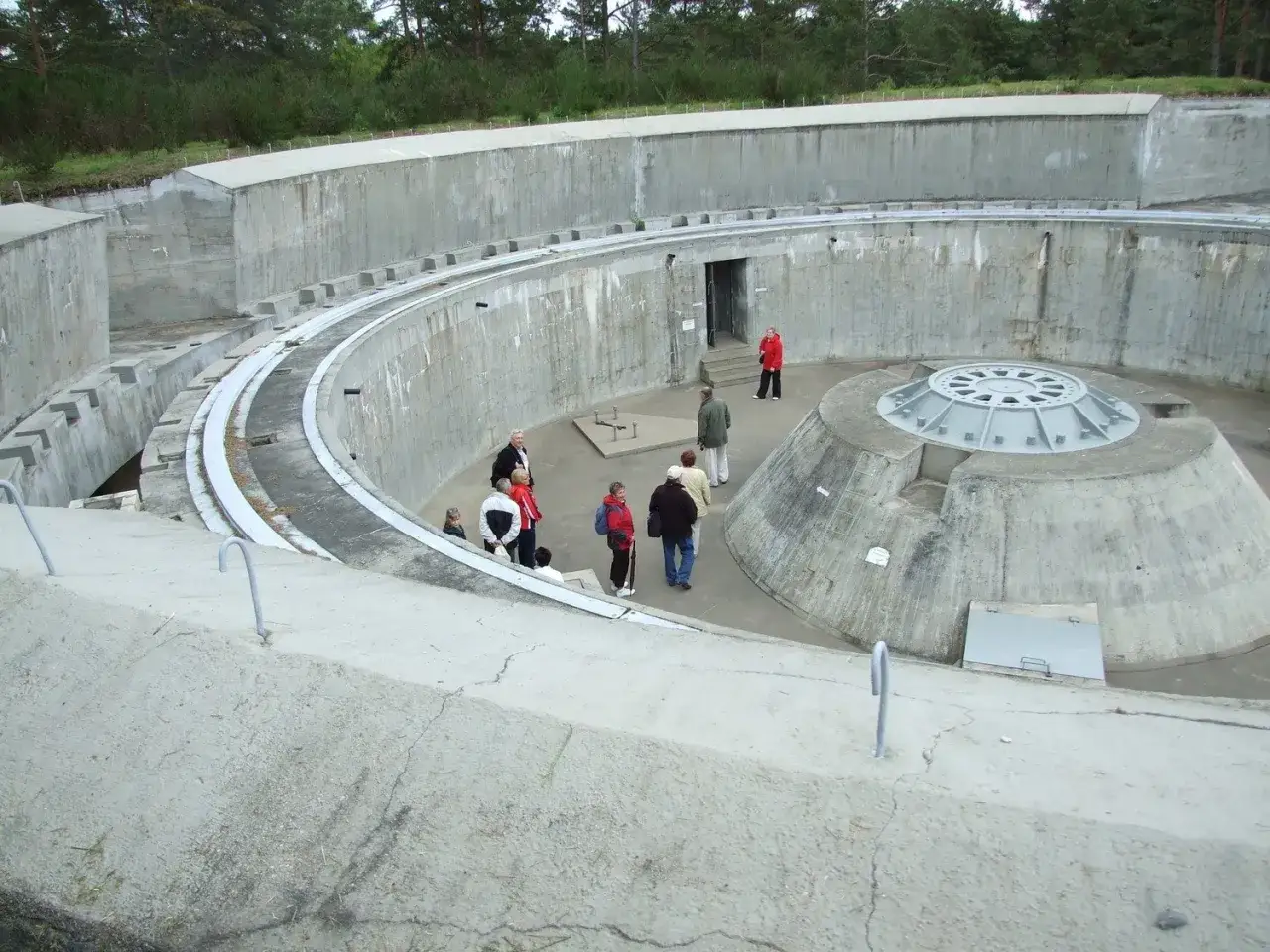 Zwiedzający w muzeum obrony wybrzeża w Helu oglądają betonową konstrukcję z metalową kopułą.