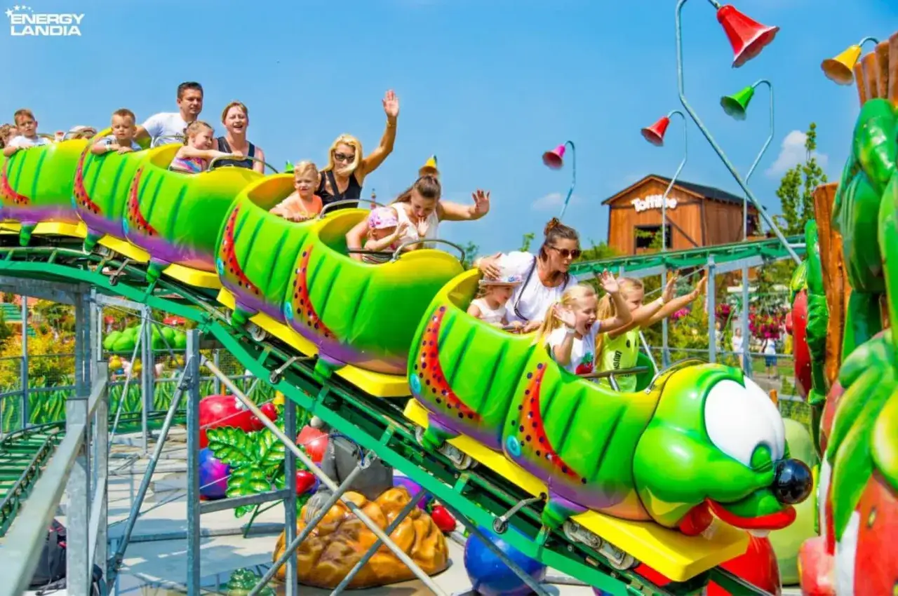 Energylandia atrakcje dla dzieci do 120 cm: wesołe gąsienice wiozą uśmiechnięte maluchy na kolejce górskiej.