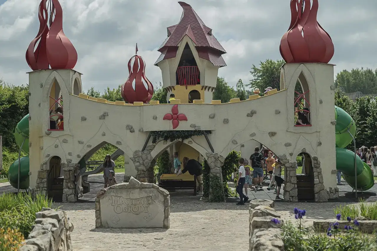 Dzieci bawią się w bajkowej scenerii, przypominającej zamek z czerwonymi, cebulastymi wieżami. To prawdziwa magiczna kraina pełna śmiechu i zabawy.