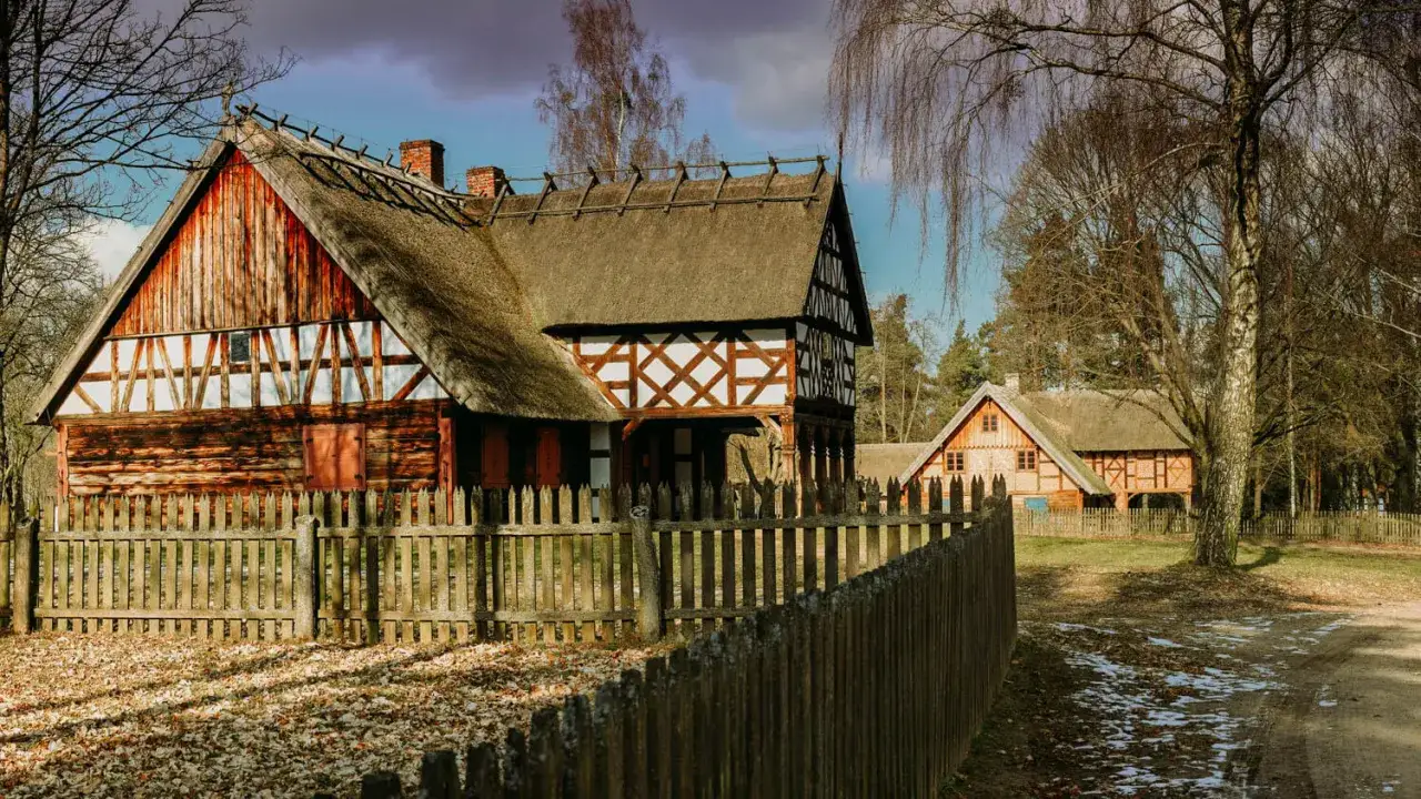 Drewniane chaty z krytymi strzechą dachami, otoczone płotem, tworzą urokliwy krajobraz. To jedne z wielu olsztynek atrakcji.