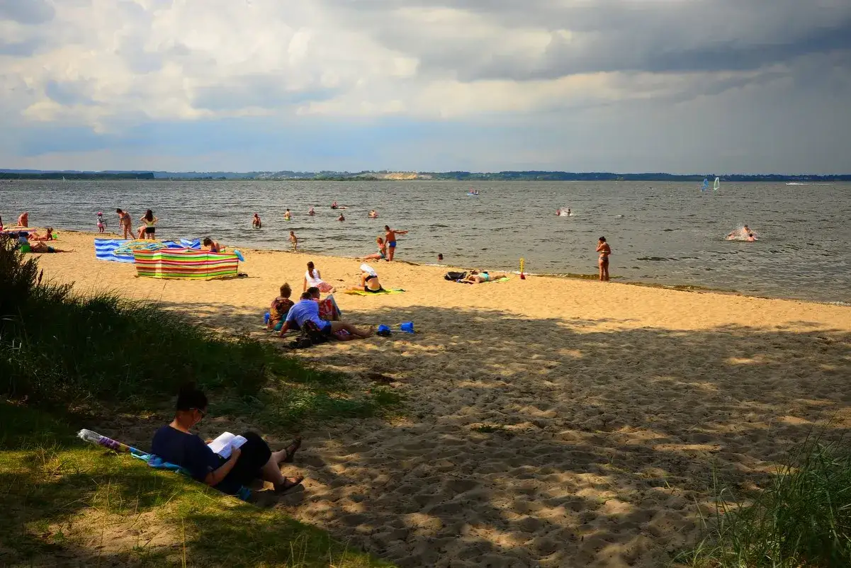 Plaża w Rewalu tętni życiem. Ludzie opalają się, kąpią i relaksują. To idealne miejsce na letnie atrakcje.