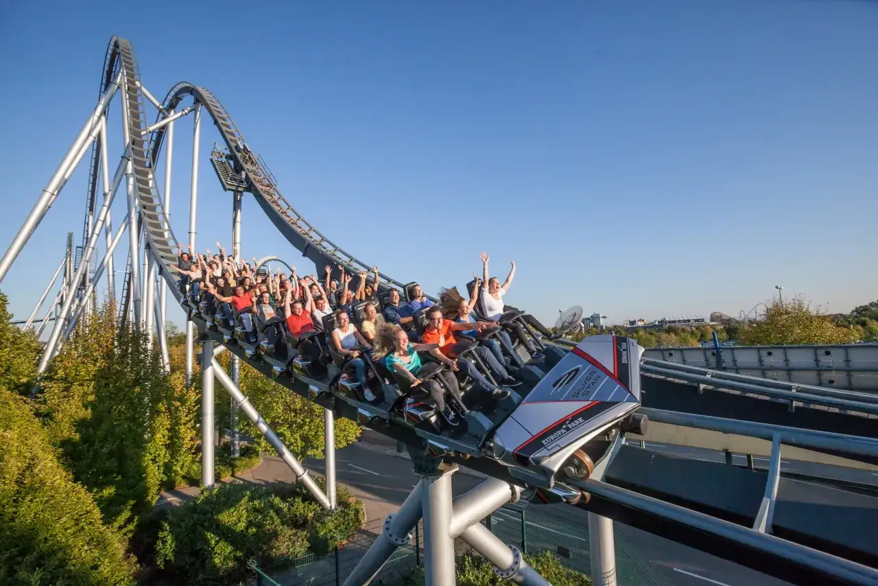 Wesoła kolejka górska Silver Star w Europa Park Niemcy z pasażerami z podniesionymi rękami.