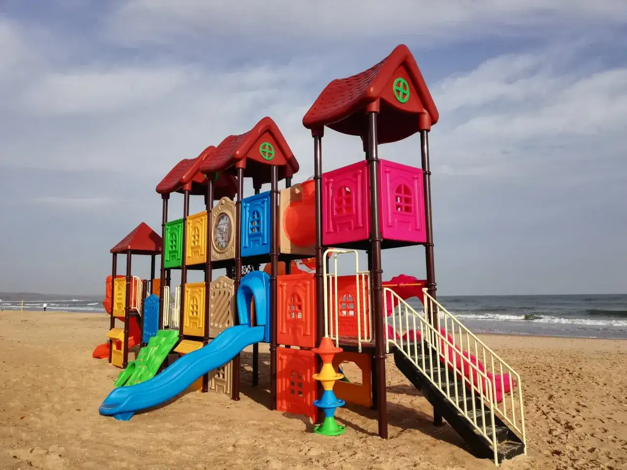 Kolorowy plac zabaw na plaży, idealne jelitkowo atrakcje dla dzieci. Zjeżdżalnie, drabinki i domki czekają na letnie zabawy nad morzem.
