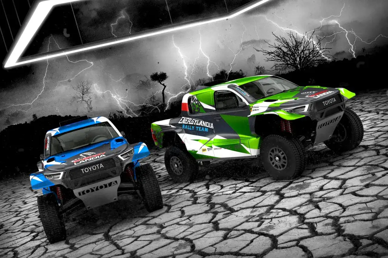 Dwa samochody terenowe Energylandia Rally Team w jaskrawych barwach, gotowe do rajdu na tle burzowego nieba.