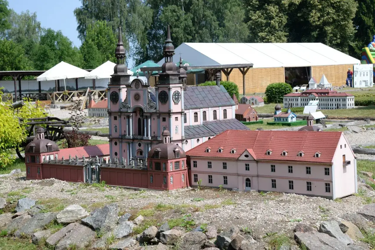 Mazurolandia i park miniatur Warmii i Mazur prezentuje miniaturowe budowle, w tym barokowy kościół i klasztor, w otoczeniu zieleni.