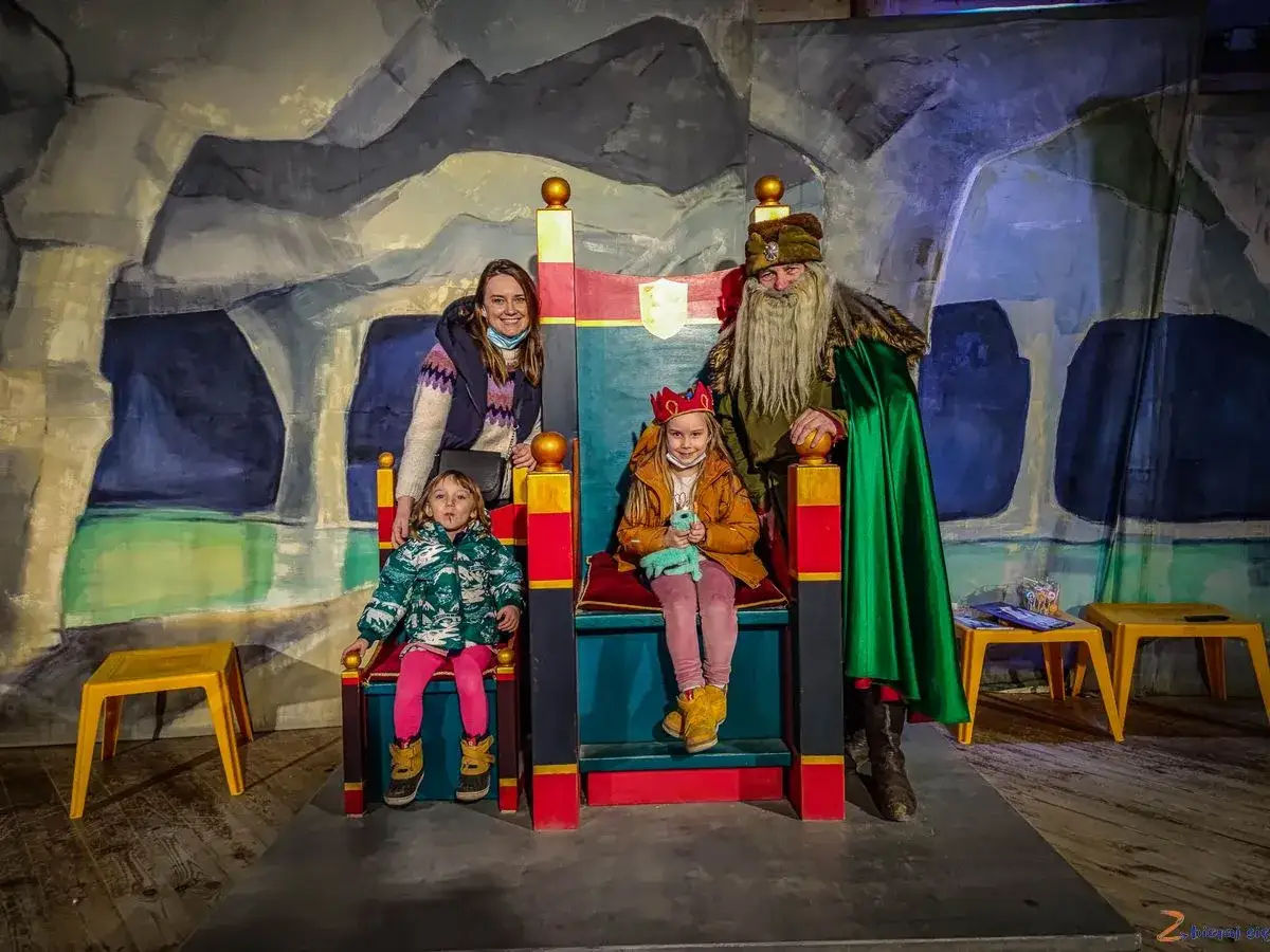 Rodzina w kopalni soli w Wieliczce spotyka króla. Dzieci siedzą na tronach, a mama i król pozują do zdjęcia.