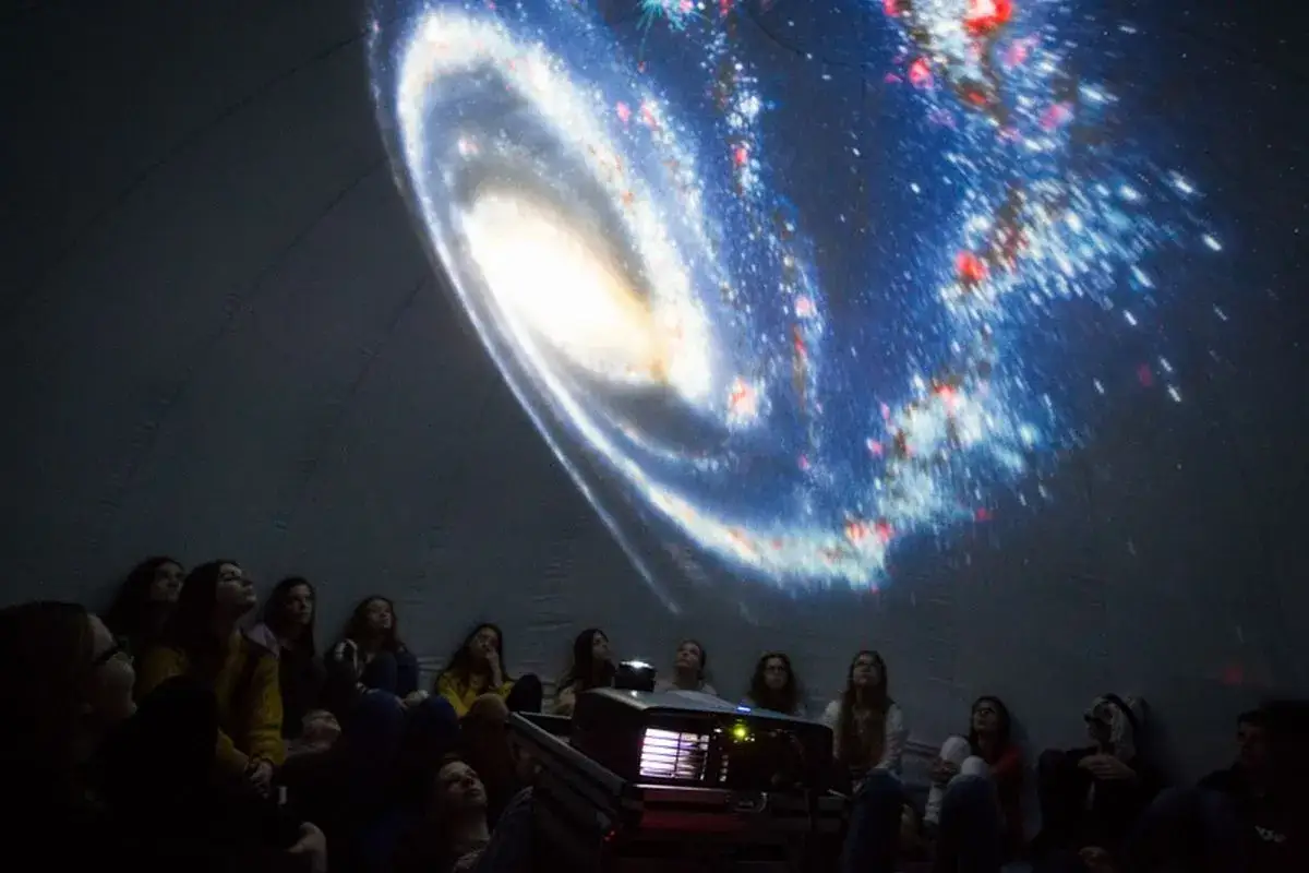 Dzieci w planetarium z zachwytem oglądają projekcję galaktyki. Niezapomniana podróż w kosmos dla najmłodszych odkrywców.