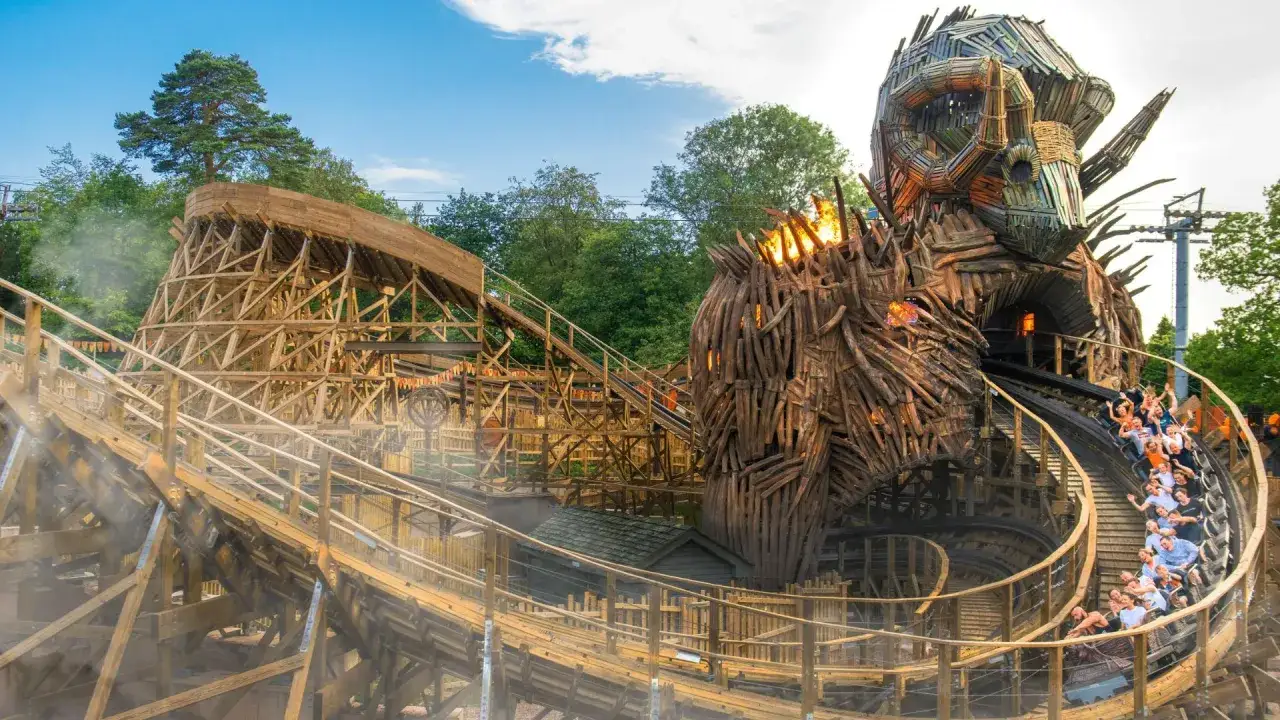 Drewniany rollercoaster w parku rozrywki w Londynie, przejeżdża przez gigantyczną, płonącą głowę stwora.