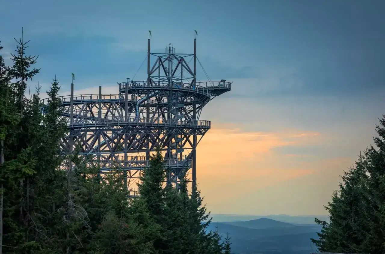 Imponująca konstrukcja skywalk w Czechach, wznosząca się ponad lasem, zaprasza do podziwiania krajobrazu o zachodzie słońca.