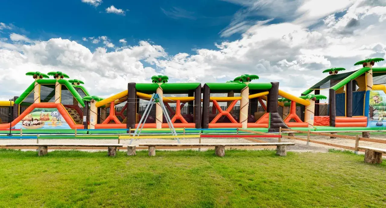 Kolorowy park rozrywki zachodniopomorskie z dmuchanymi zjeżdżalniami i placem zabaw w dżunglowym stylu.