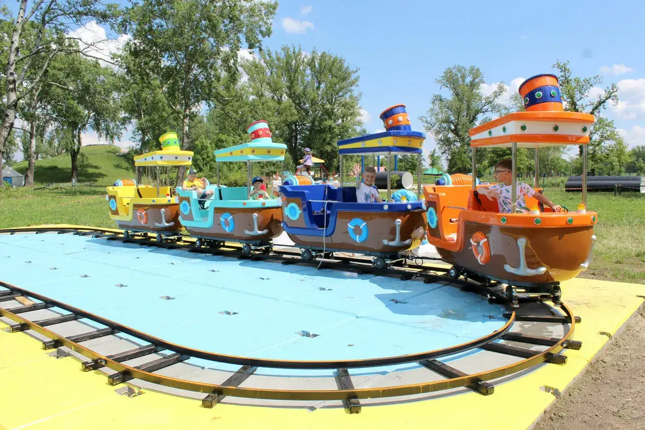 Kolejka w kształcie łódeczek z dziećmi na pokładzie, wesoło mija się na torach w stężyca park rozrywki.